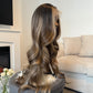 Product Side view of a balayage wig with natural waves, highlighting the seamless lace front and realistic texture